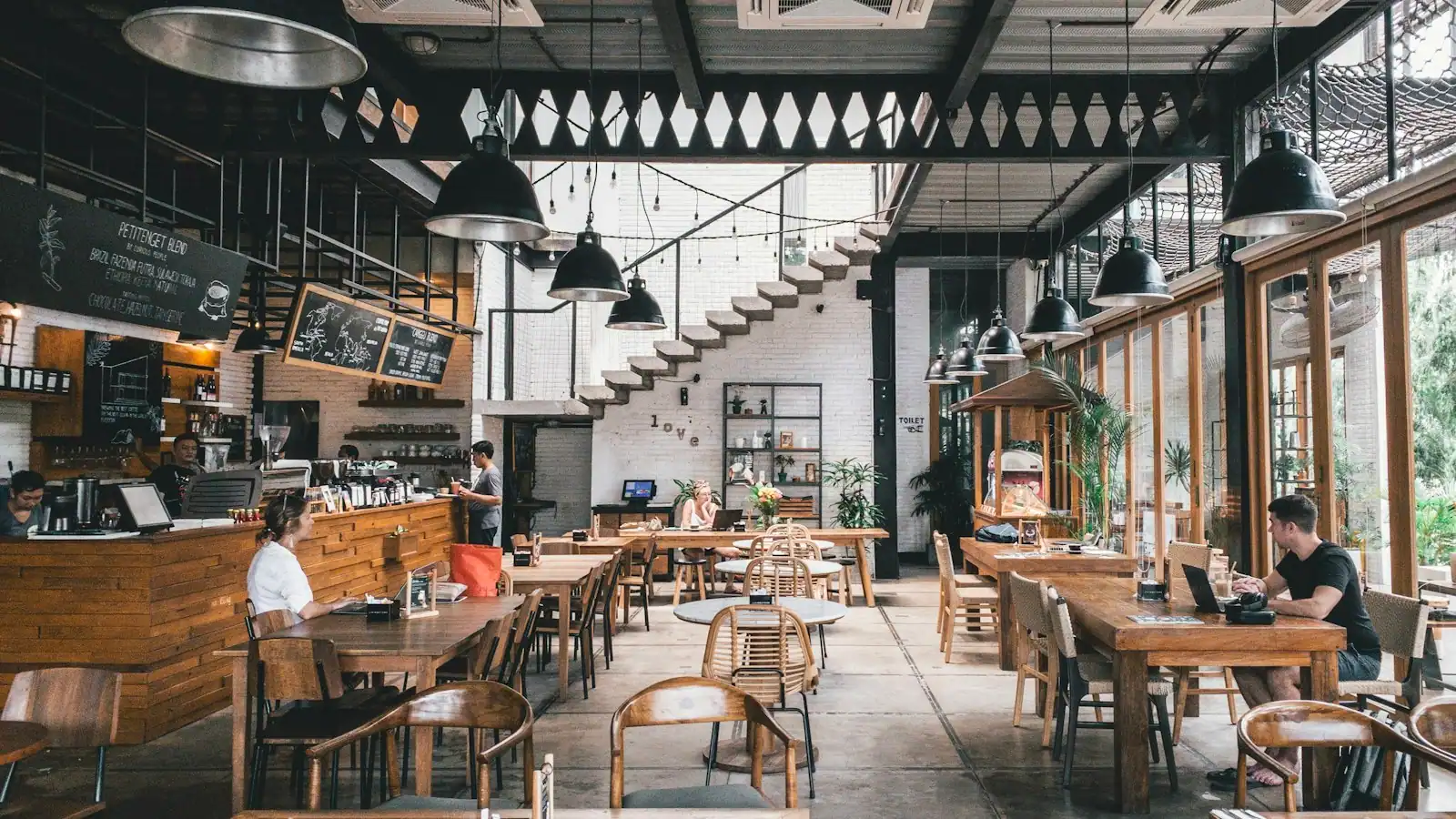 A bright, open dining room with long communal tables and large windows