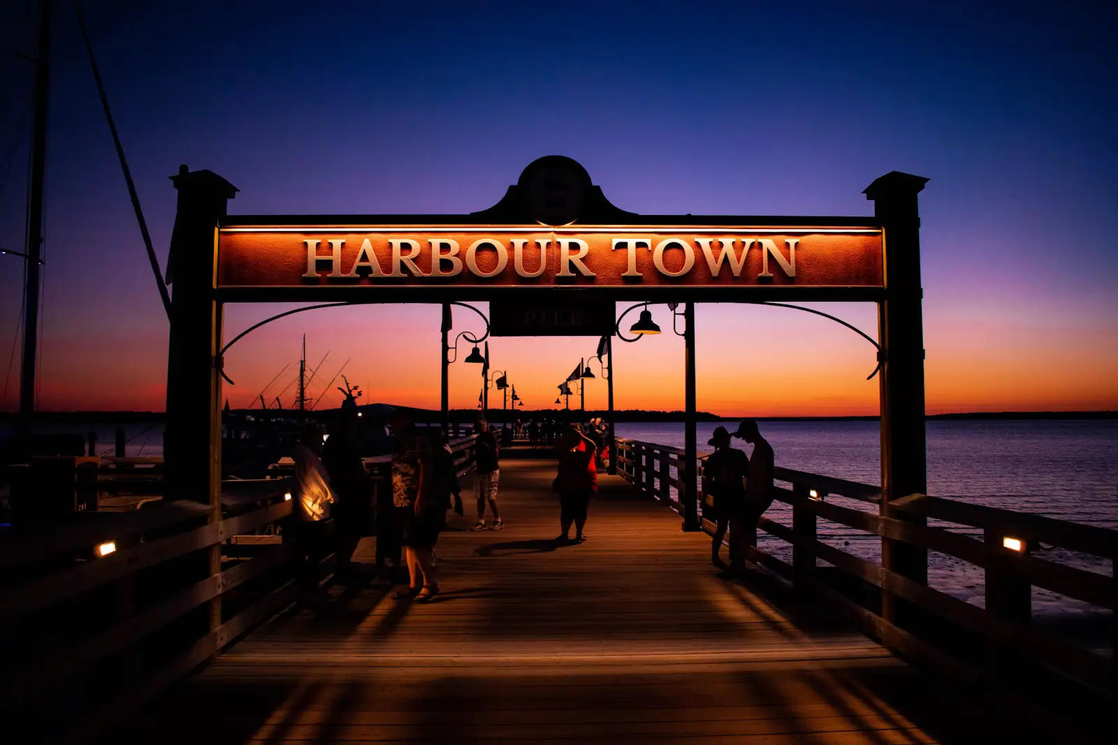 People gathered on a wooden dock watching the sun go down over calm water